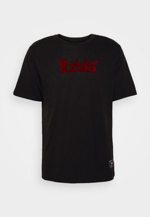 T-shirt noir à manches courtes Levi's avec un logo gothique rouge centré sur la poitrine et une petite étiquette rectangulaire près de l'ourlet inférieur sur le côté droit.