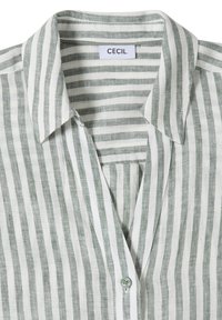 Chemise à col avec des rayures verticales grises et blanches, un seul bouton visible et une étiquette "CECIL" à l'intérieur du col.