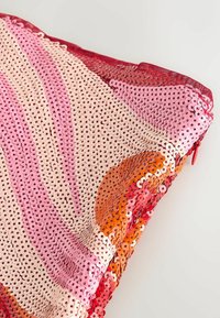 Bolso de mano cubierto de lentejuelas brillantes en tonos rosa, rojo, naranja y beige con una cremallera roja sobre un fondo blanco.