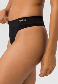 Black thong underwear featuring a wide waistband with the "BeeDees" logo. Smooth texture with minimal coverage and a sleek design.
