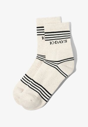 Weiße Sportsocken mit schwarzen horizontalen Streifen an Bündchen, Knöcheln und Zehen, mit dem Schriftzug "10 DAYS" am oberen Bündchen.