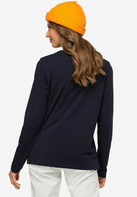 Granatowa koszulka z długim rękawem, wykonana z miękkiej bawełny, z okrągłym dekoltem i luźnym krojem, w połączeniu z jasnopomarańczową, prążkowaną czapką.