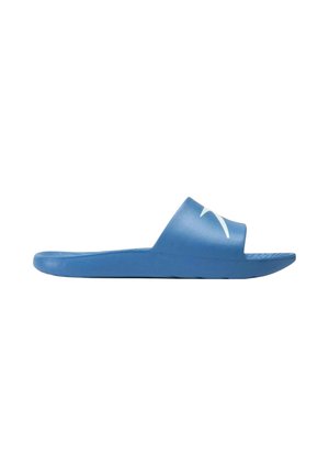 Sandalo blu slip-on con ampia fascia che presenta un logo bianco stilizzato sulla parte superiore, visto di lato su sfondo bianco.