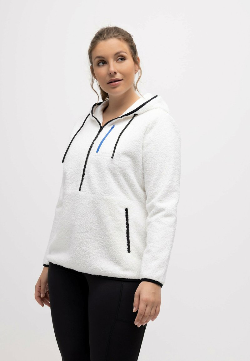 Sudadera con capucha de forro polar blanco con acentos negros, bolsillo frontal con cremallera y capucha ajustable con cordón. Tela texturizada y ajuste holgado.