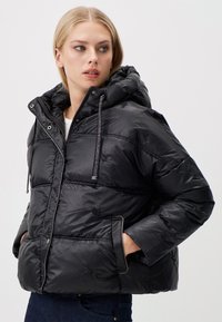 Zwarte pufferjack met een capuchon, gemaakt van glanzende, gewatteerde stof, met elastische trekkoorden, rits- en drukknoopsluiting, en dubbele voorkwesten.