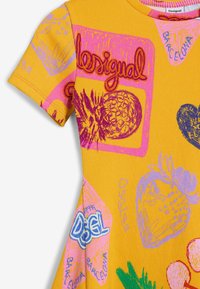 T-shirt giallo a coste con maniche corte, caratterizzato da vivaci grafiche rosa e blu di ananas, fragole e testo del logo.