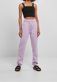 Svart crop-top med fyrkantig halsringning, kombinerad med ljuslila joggerbyxor med elastisk midja och snörning. Svarta sandaler.