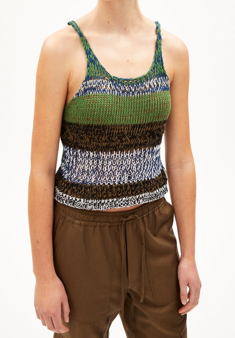 Femme portant un haut sans manches en maille rayée multicolore et un pantalon marron avec cordon de serrage.