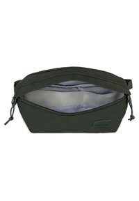 Sacca in tessuto verde scuro con chiusura a zip, forma curva, fodera interna grigia e piccolo dettaglio etichetta sul lato.