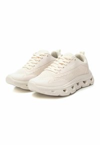 Zapatillas ligeras beige con paneles de malla, acentos texturizados, cuello acolchado y una suela acolchada con recortes distintivos.