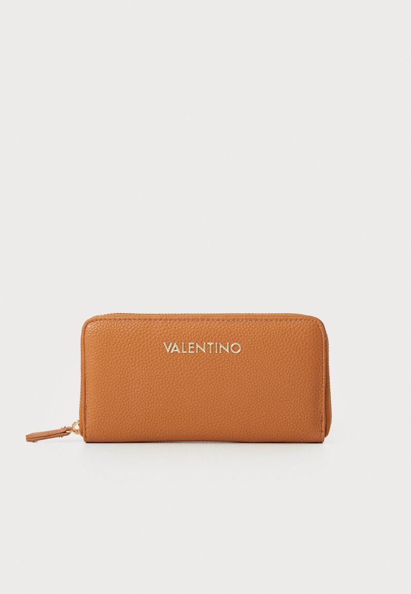 Brūns ādas maciņš ar teksturētu virsmu, zelta "VALENTINO" logo priekšpusē, ar rāvējslēdzēju un mazu pomponu detaļu uz rāvējslēdzēja.