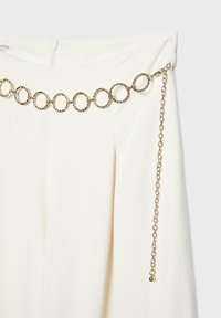 Hvid nederdel med et guldkædebælte med store runde led og en justerbar hængende kæde med en lille rund charme.