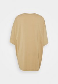 T-shirt beige oversize à manches courtes présenté de dos avec un col rond et une coupe ample sur fond blanc.