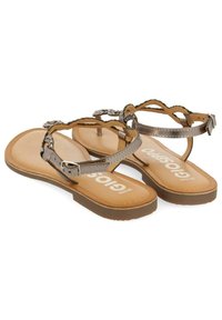 Sandalias marrones con correas metálicas plateadas, que presentan un diseño trenzado y hebilla ajustable. Suela texturizada con la marca visible.