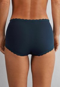 Marinblå trosor med en scallop-lace midjeband och slät tyg, designade i en hipsterstil, tight passform och minimal täckning.