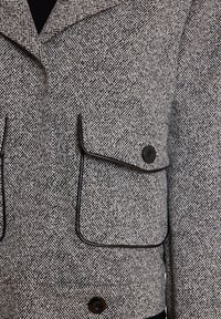 Zwart-wit houndstooth-jack met een kraag, twee klepzakken, zwarte piping en ronde knopen. Geweven stof, slim-fit ontwerp.