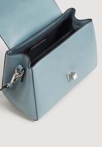 Sac à main en cuir bleu clair à la forme structurée, doté d'une fermeture carrée en argent, d'un intérieur noir et d'une bandoulière amovible.