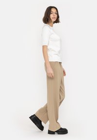 White short-sleeve top with a round neckline, paired with beige wide-leg pants and chunky black platform shoes.