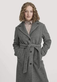 Grauer Wollmischmantel mit tailliertem Gürtel, Kegellappen und Seitentaschen. Mit Knopfleiste und weicher, strukturierter Oberfläche.