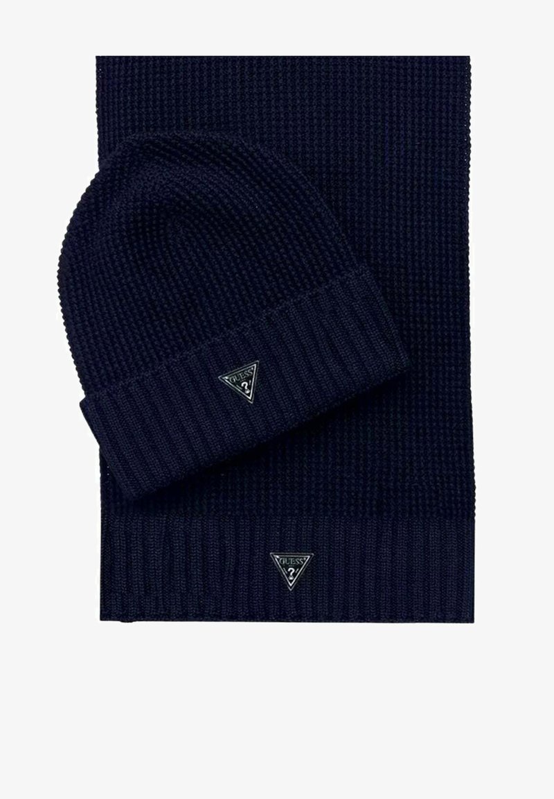 Set composto da berretto a coste in maglia blu navy e sciarpa abbinata, entrambi con una toppa triangolare con logo. Texture morbida e materiale spesso.
