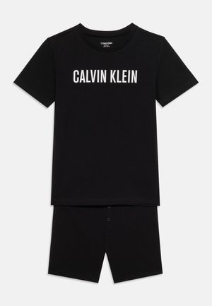 T-shirt noir à manches courtes avec l'inscription "CALVIN KLEIN" en texte blanc, associé à un short noir assorti avec fermeture à boutons.