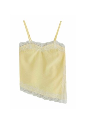 Giovane donna con lunghi capelli biondi che indossa un top giallo bordato di pizzo, che guarda leggermente verso l'alto con un'espressione neutra.