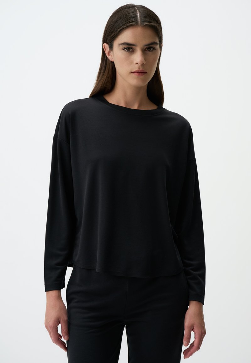 Schwarzes Langarmshirt aus glattem Stoff, mit lockerer Passform, rundem Ausschnitt und abfallenden Schultern. Einfaches, minimalistisches Design.