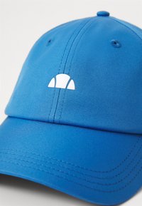 Blue cap made of smooth fabric featuring a white logo on the front, with a structured shape and stitched detailing along the brim.