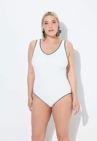 Maillot de bain une pièce blanc à côtes avec un décolleté en V profond, finition festonnée noire le long des bords et bretelles ajustables. Texture lisse.