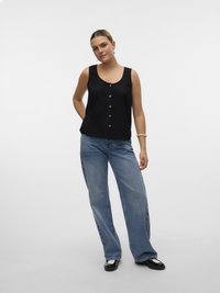 Top nero senza maniche con bottoni, abbinato a jeans larghi blu chiaro. L'outfit presenta un design minimalista e una texture morbida.