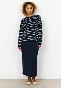 Navy striped long-sleeve top with cream stripes, paired with a solid navy skirt featuring side pockets. Light-colored flat shoes.