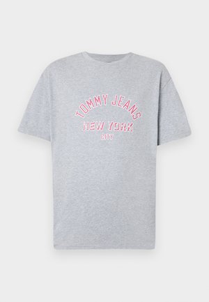 Šedé bavlnené tričko s krátkymi rukávmi a okrúhlym výstrihom. Na strede je vyšívaný nápis "TOMMY JEANS NEW YORK CITY" v ružovej farbe.