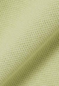 Hellgrüner Stoff mit feiner, dicht gewebter Strickstruktur, im Nahaufnahme gezeigt und seine weiche und glatte Oberfläche hervorhebend.