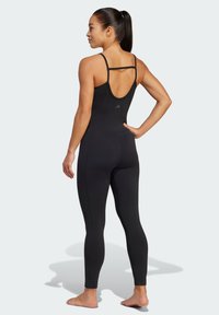 Bodysuit atlético negro con tirantes finos y diseño de espalda baja, fabricado en material elástico, con un sutil branding y detalles en las costuras.