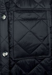 Černá prošívaná bunda s diamantovým vzorem, lesklým povrchem, velkou náprsní kapsou a kovovými patentními knoflíky.