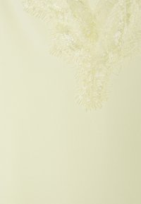 Delikat krämfärgad tyg med blommig spetskant som har fina vågiga kanter och intrikata stygnmönster.