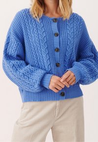 Blå stickad cardigan med strukturerade mönster, med rund halsringning, långa ärmar och mörka knappar framtill.