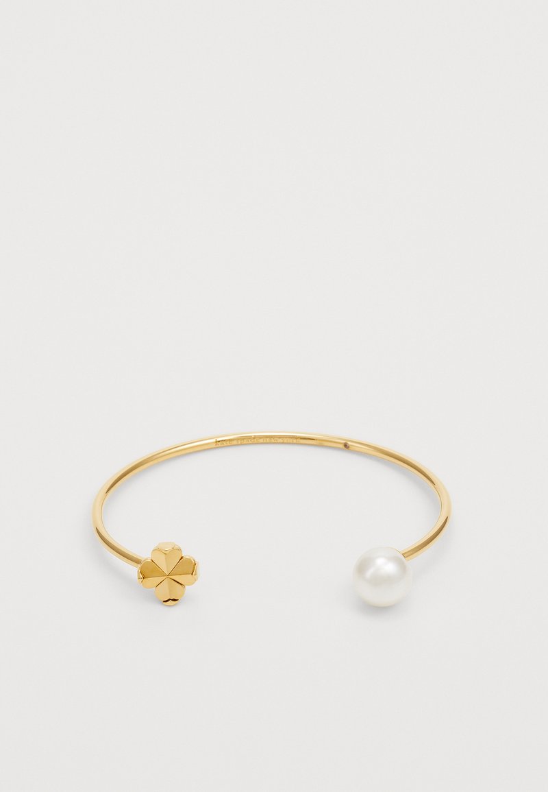 Pulseira de pulso em metal dourado com um detalhe floral em uma extremidade e uma pérola branca redonda na outra. O design é elegante e minimalista.