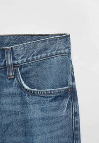 Jeans in denim con un lavaggio blu sbiadito, caratterizzati da un design a cinque tasche, cuciture visibili in filo arancione e una vestibilità a gamba dritta.