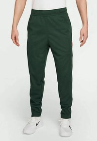 Σκούρο πράσινο παντελόνι jogger φτιαγμένο από μαλακό ύφασμα, με ελαστική μέση, πλαϊνές τσέπες και μια μικρή λεπτομέρεια λογότυπου στο πάνω μέρος του μηρού.