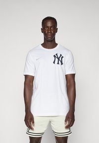 White cotton t-shirt with a navy New York Yankees logo on the chest and a Nike swoosh on the shoulder. Short sleeves and a crew neck design.