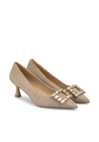 Tacchi a punta in suede beige con tacco basso a blocco, decorati con una fibbia in strass trasparenti sulla parte anteriore.