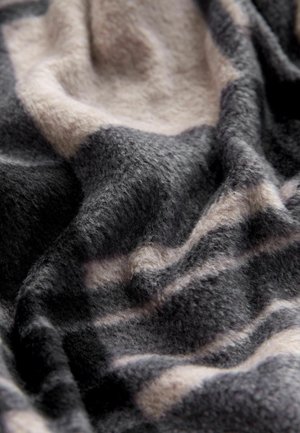 Manta suave y texturizada con un patrón abstracto en negro, gris y beige, mostrando pliegues y una superficie de felpa.