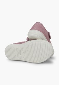 Pink canvas shoes with a textured finish, white rubber soles featuring horizontal grooves for traction, and a Velcro strap for easy fastening.