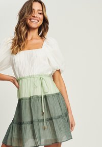 Vestido ligero en capas con escote cuadrado. Presenta bloques de color en blanco, verde claro y verde oscuro; cintura elástica y detalle de lazo.
