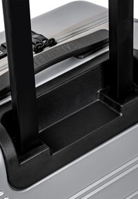 Silberner Hartschalenkoffer mit strukturierten Oberflächen, ausgestattet mit schwarzen Teleskopgriffen, Reißverschluss und einem aufgedruckten Logo auf der Oberseite.