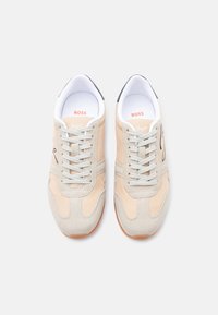 Μπεζ και ανοιχτό γκρι αθλητικά παπούτσια με κορδόνια, λευκή εσωτερική επένδυση, επίπεδη καφέ σόλα και λογότυπο "Boss" στις εσωτερικές σόλες και τις γλώσσες.