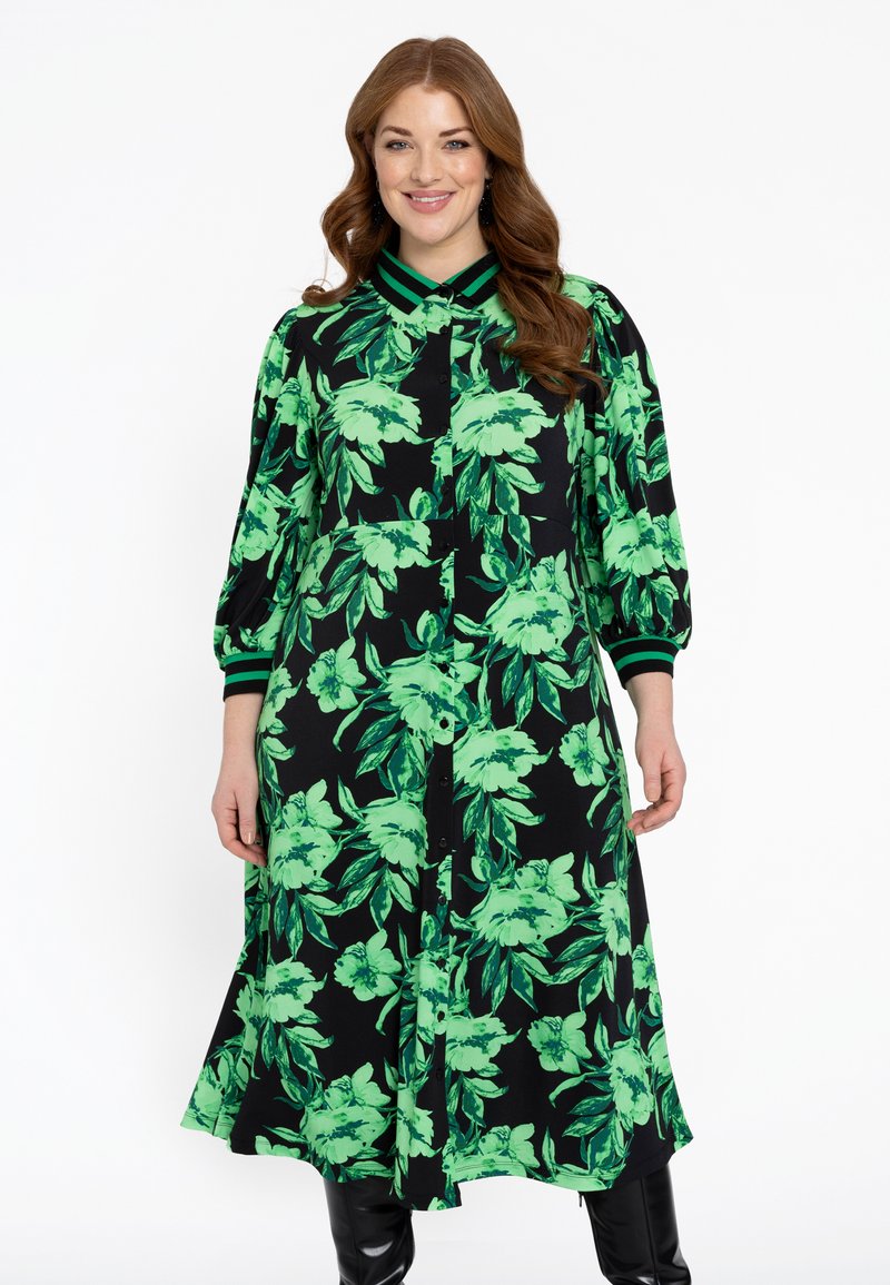 Blumenhemdkleid in Schwarz mit lebhaftem grünen Blatt- und Blumenmuster. Verfügt über eine Knopfleiste, einen Kragen und gestreifte Akzente an den Manschetten.