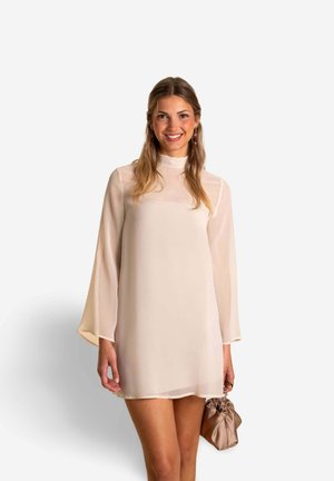 Robe beige courte avec de longues manches évasées. Fabriquée en tissu transparent, elle présente un col montant et est associée à un petit sac doux.