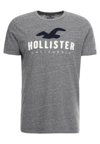 Šedé bavlněné tričko s kulatým výstřihem a krátkými rukávy, na přední straně s potiskem "HOLLISTER CALIFORNIA" v bílé a tmavě modré barvě.